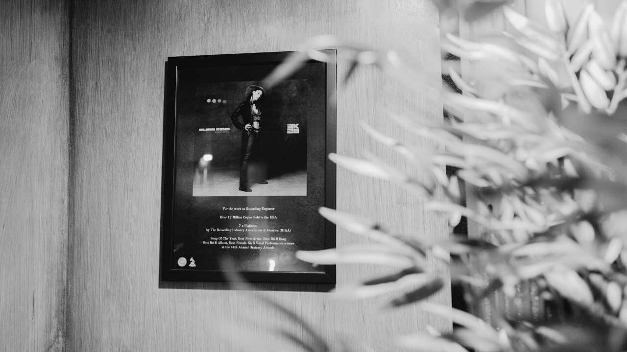 A framed plaque honoring work with Alicia Keys, displayed on the wall of a professional recording studio.