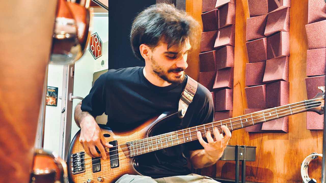 An artist playing a bass guitar in a professional studio with acoustic paneling, focused on capturing the perfect sound.