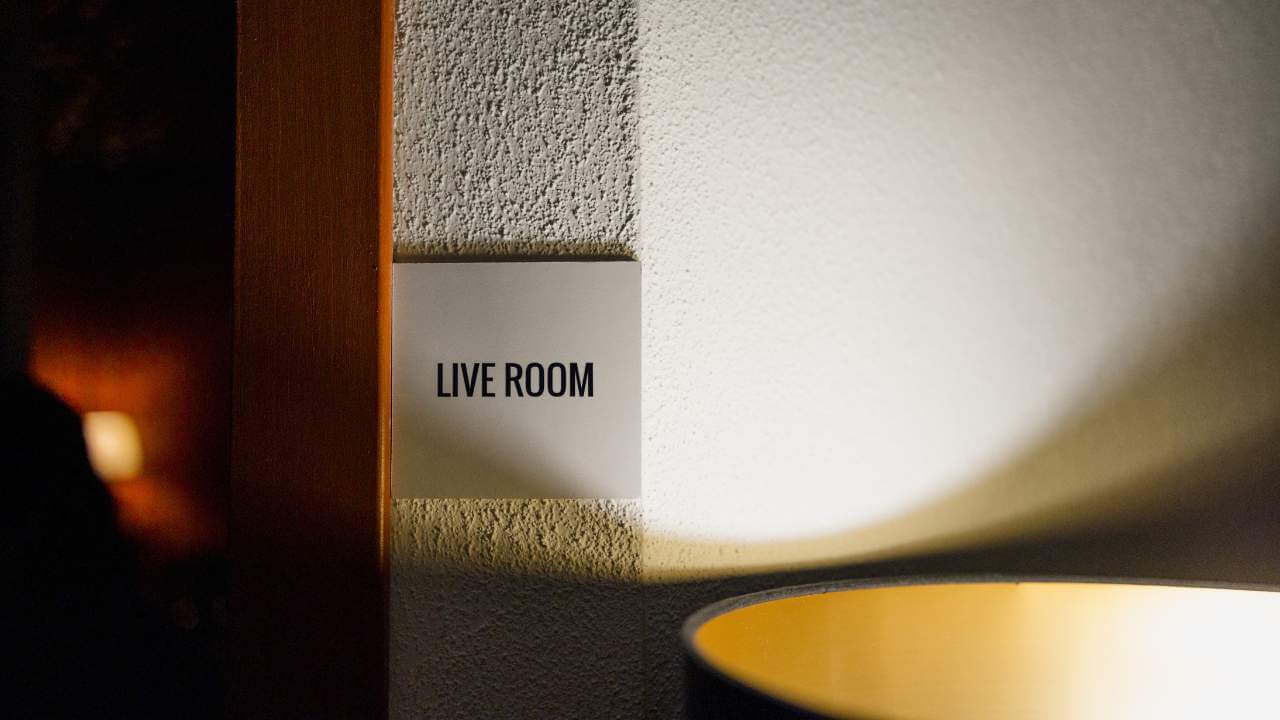 A close-up of a 'Live Room' sign in a recording studio, illuminated by warm ambient lighting.