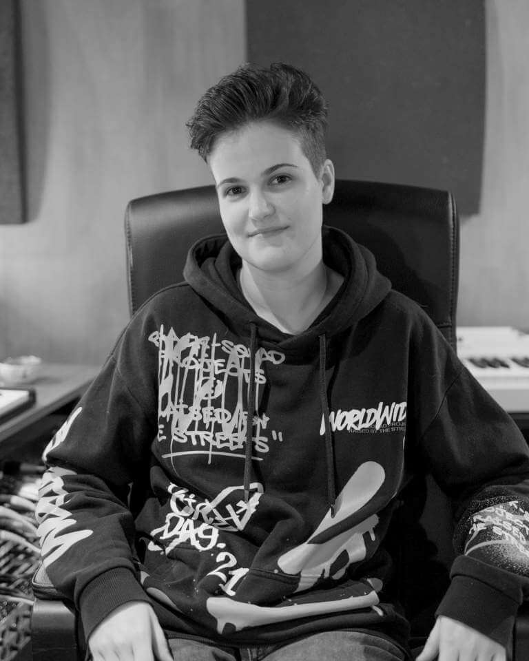 Patrícia Rosa, music producer at Sound Pressure Studios, sitting confidently in the control room with studio equipment in the background.