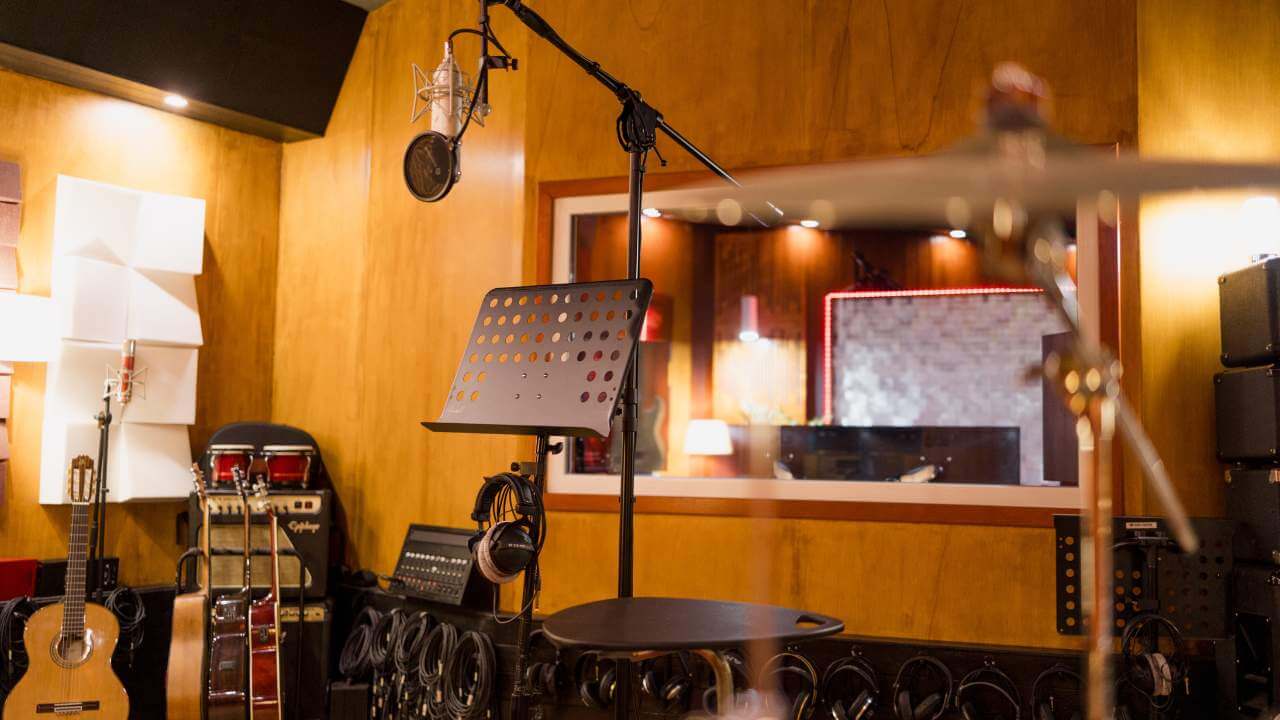 A professional recording studio with guitars, drums, microphones, and a music stand in a well-equipped space.