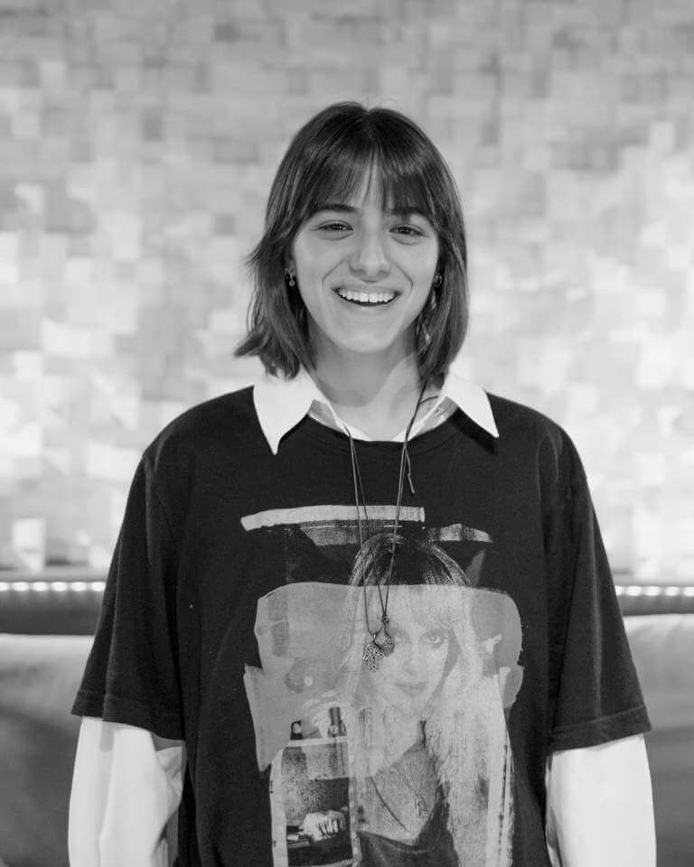 Sílvia Graça, music producer at Sound Pressure Studios, sitting in the control room with professional audio equipment and studio decor in the background.