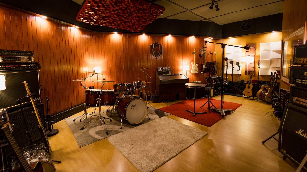 Live room at Sound Pressure Studios featuring drums, guitars, amplifiers, microphones, and acoustic treatments for professional recording sessions.